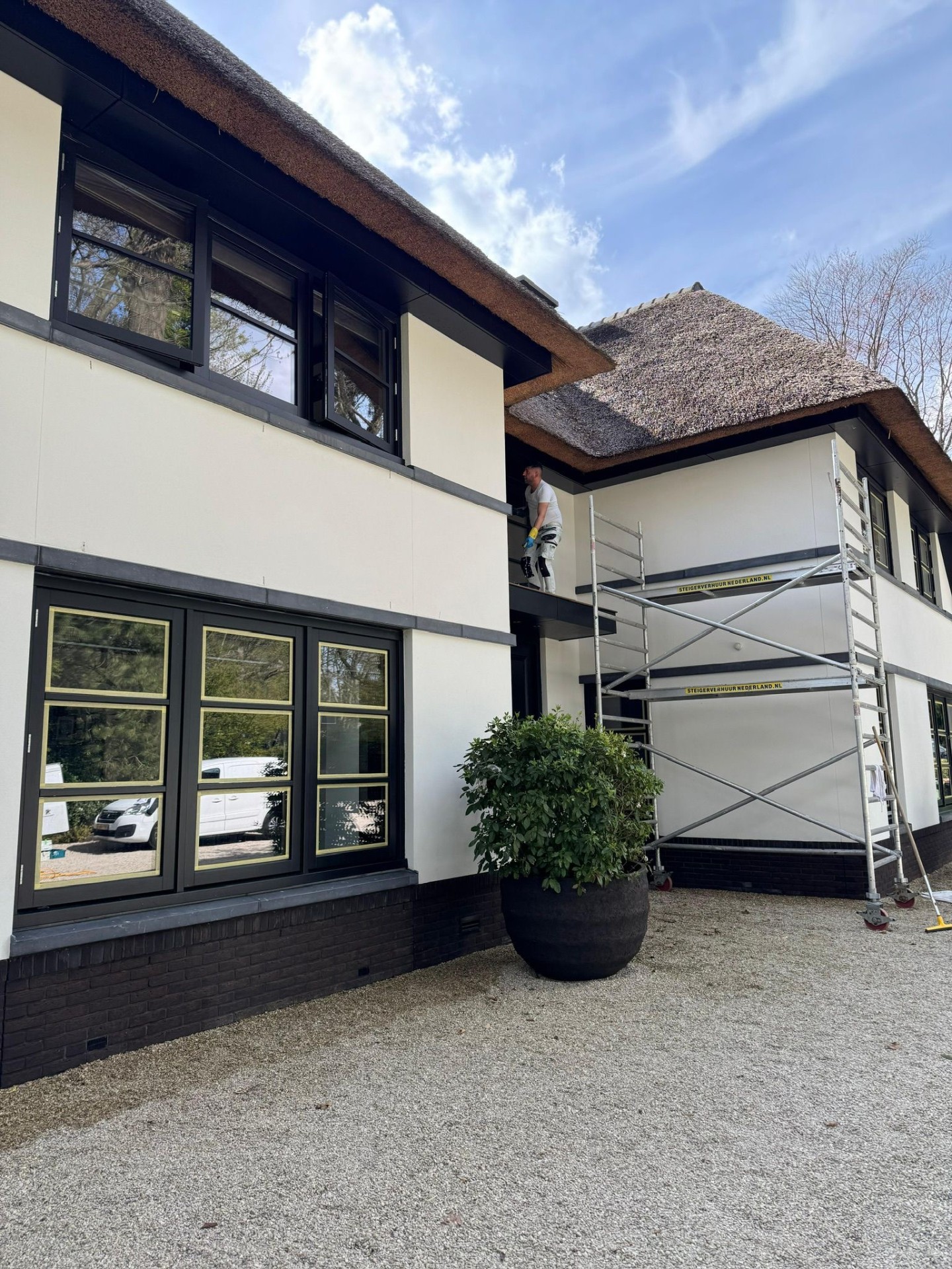 Buitenschilderwerk aan rietgedekte villa met steiger